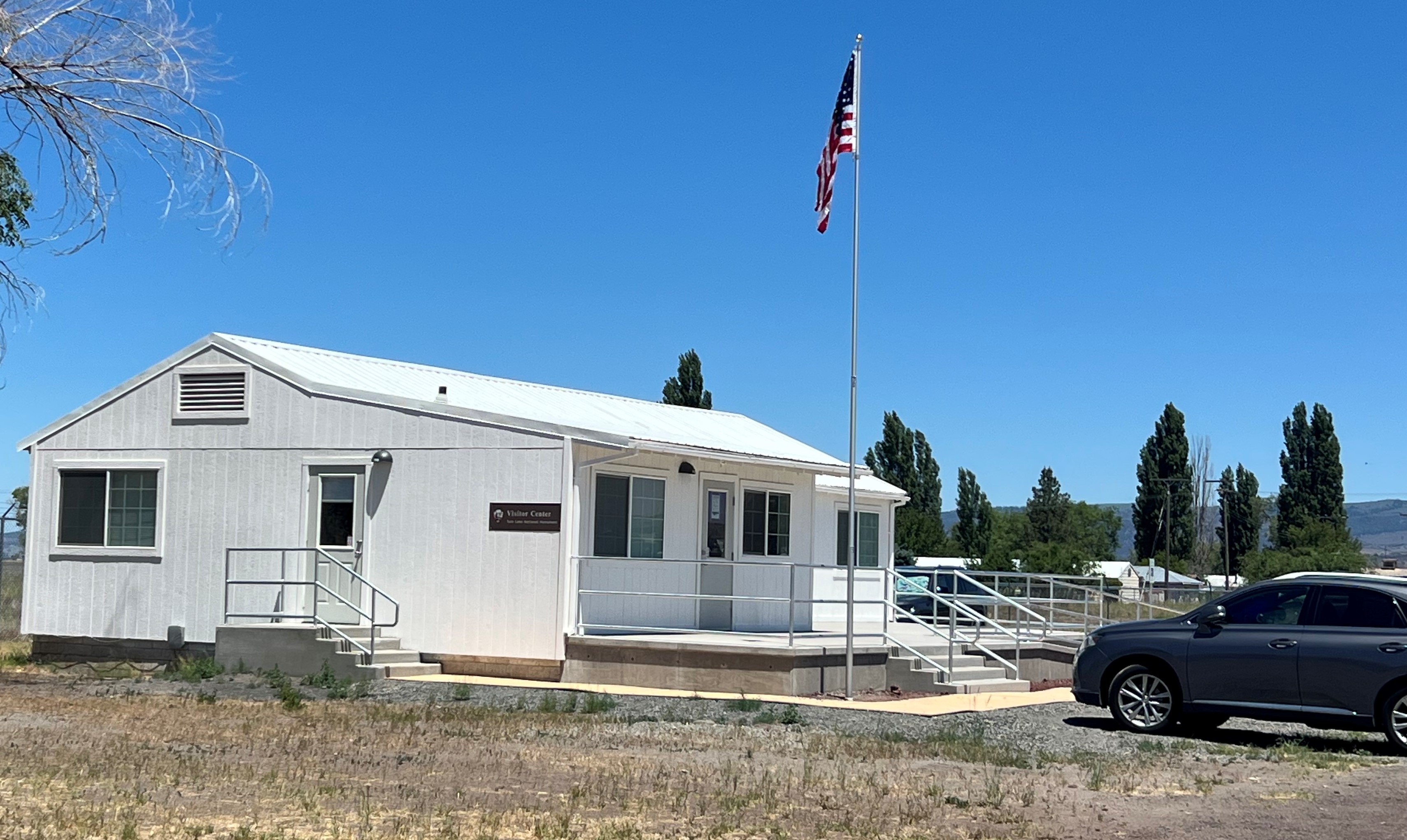 A white house looking building with small concrete steps and walk way leading to two doors.