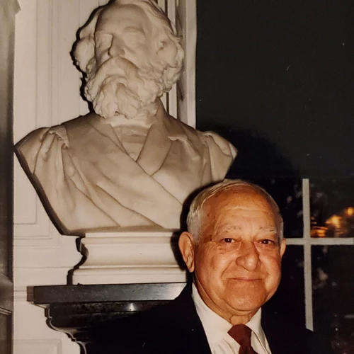 Older man in suit posed in front of marble bust of Henry Wadsworth Longfellow