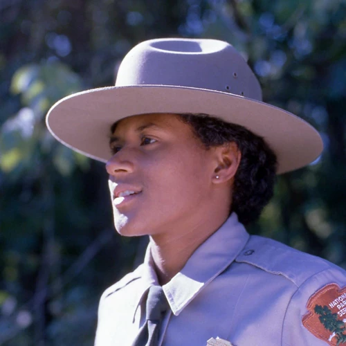 Young Black female uniformed ranger in gray shirt, green tie, and gray felt hat with broad rim.