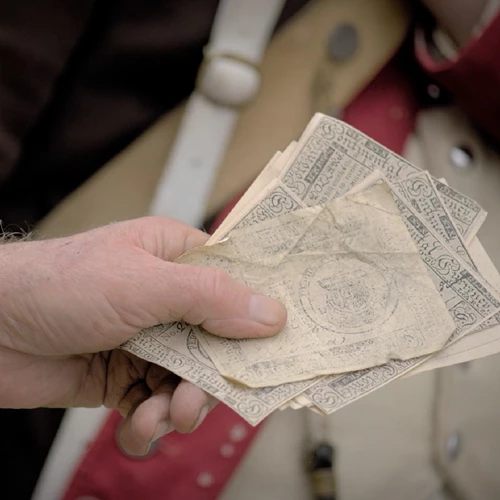A closeup of a man’s hand holding several pieces of paper money.