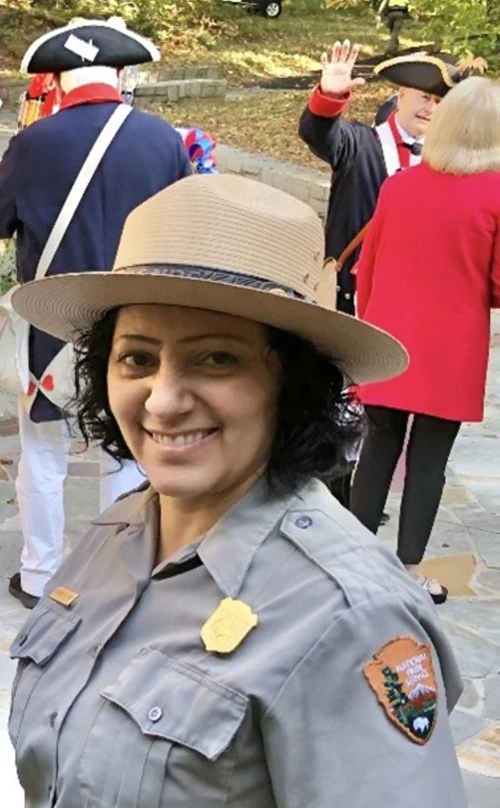 A ranger in a flat hat smiles at the camera