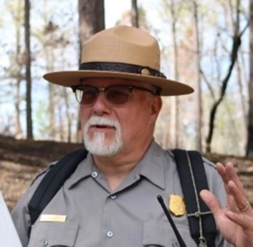 A ranger in a flat hat and shaded glasses.