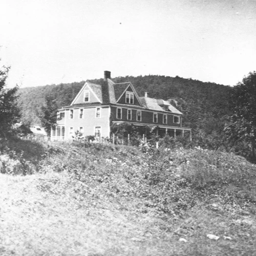 Black and white photo of Zane Grey's house, a three-story house with white trim on a hill with trees
