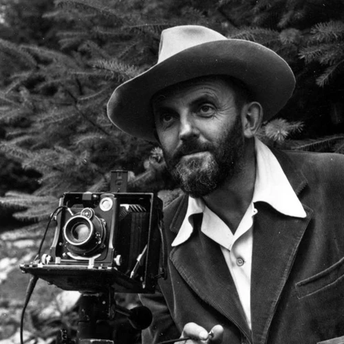 A man in a hat poses in front of a camera.