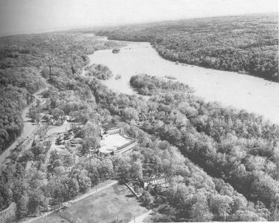 An aerial view of the landscape shows the river, canal clearing in the trees, and amusement park.