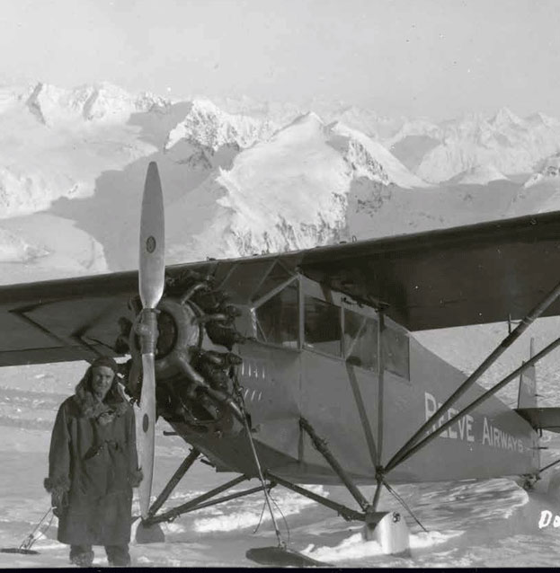 black and white image of a man standing next to a propeller airplane