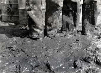 closeup of the feet of men standing in mud