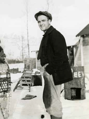 black and white photo of a man standing near a barrel and snowshoes