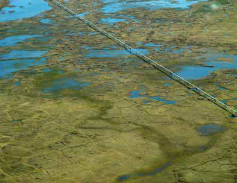 aerial view of a pipeline traveling across a landscape of bogs and lakes