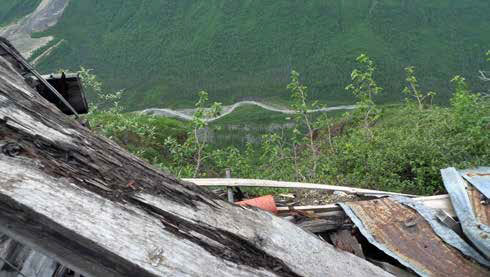 Looking downhill from the top of a sheet metal roof at a creek or narrow road