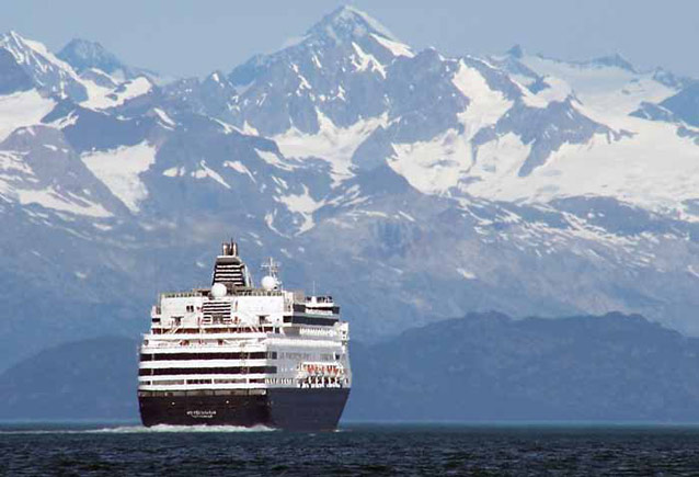a huge cruise ship on the ocean with snowy mountains in the distance
