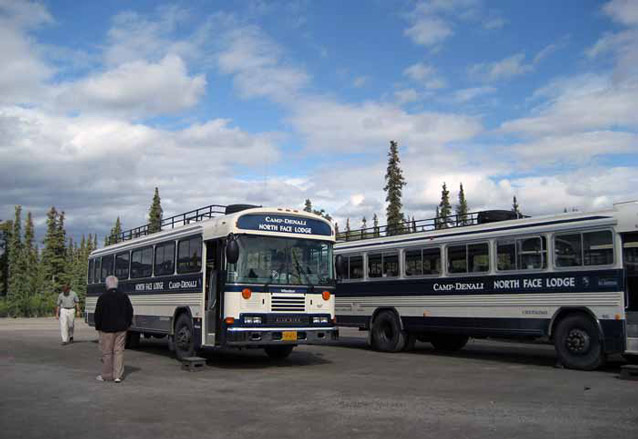 two buses in a gravel parking lot