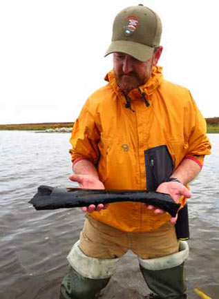 Man in a shallow lake holding a fossil