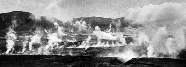 black and white image of smoke rising from a rocky landscape