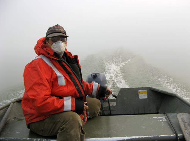 woman in a surgical mask on a boat, surrounded by thick smoke