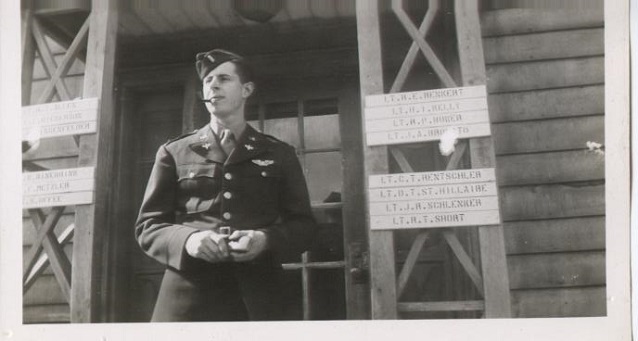 A man in uniform stands on a porch with many name signs