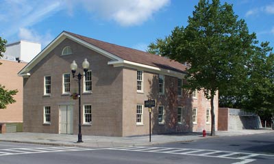 A rectangular, sand-colored two-story building sits on the corner of two streets.