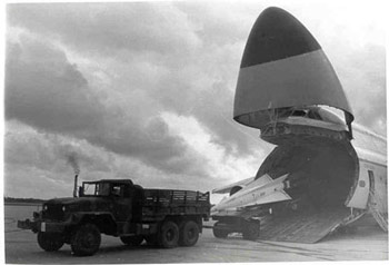 An army truck unloads a missile from an air carrier.