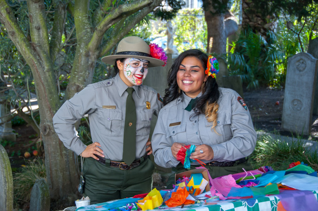 Two rangers, one wearing Dia de los Muertos make-up and both wearing colorful flowers in their hair
