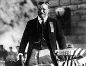 Black and white photo of President Theodore Roosevelt on the crest of Roosevelt Dam 