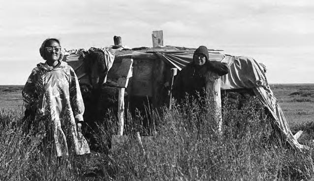 Women standing in front of a sod house.