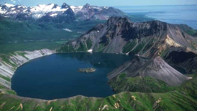 aerial view over a caldera with mountains behind it