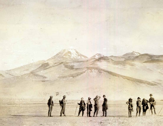 historic photo featuring a group of people with mountains in the distance