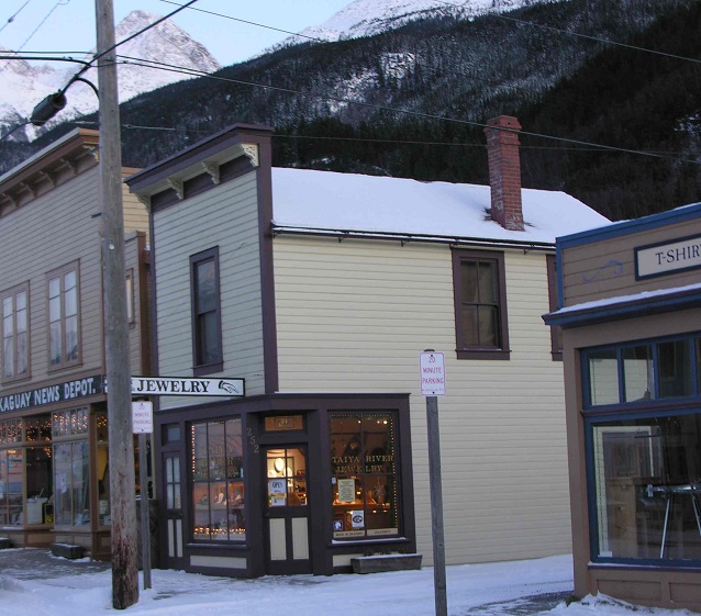 A cream colored building on a snow covered street.