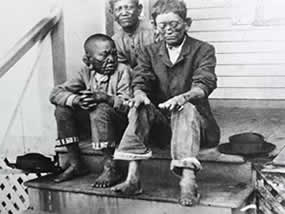 Three children sit on steps in this black and white image.
