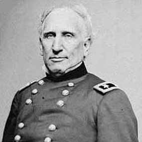 A man, shown chest-up, poses in a double-breasted military uniform