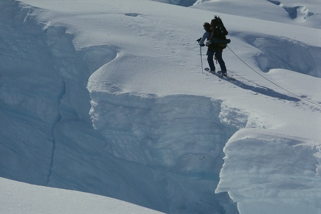A mountaineer walks beside a deep crevasse (Denali National Park, AK)