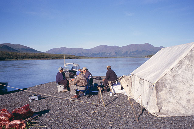 people sitting near a canvas tent near a large river