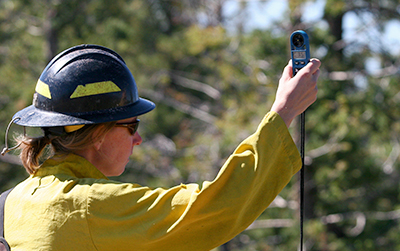 A firefighter holds up an instrument to measure wind speed.