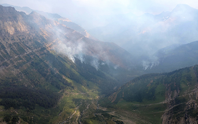 Smoke rising from steep mountainous valley.