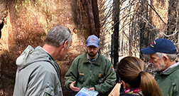A National Park Service employee speaks to two men and a woman.