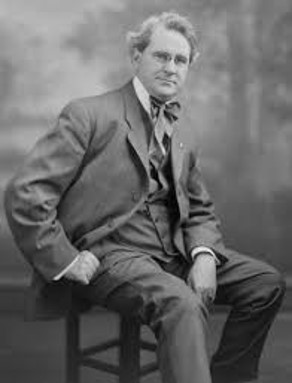 black and white portrait of man sitting on stool