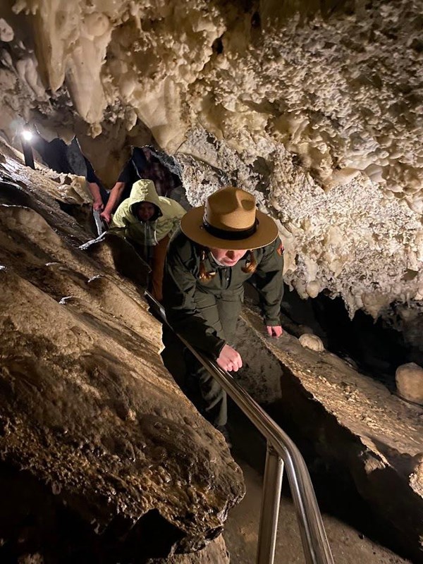 Ranger ducking and twisting to fit through a narrow cave passage.