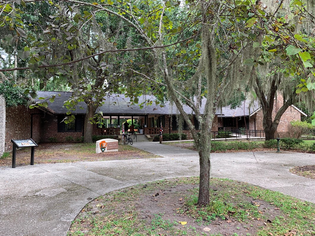 Brick building with wheelchair ramp behind a tree hung with Spanish moss