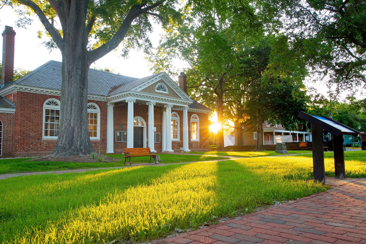 Historic Gloucester Courthouse with white columns at sunrise.