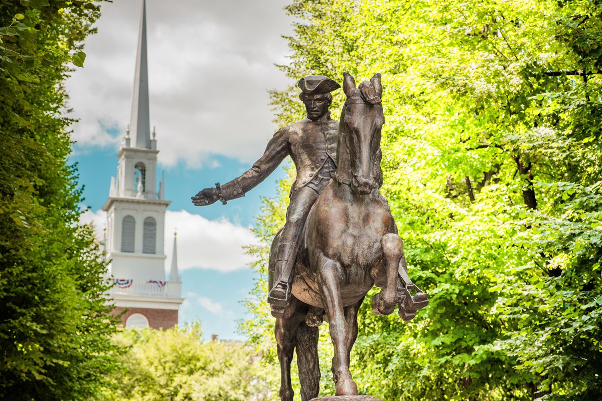 Statue of Paul Revere on horseback, with the white steeple of Old North in the background