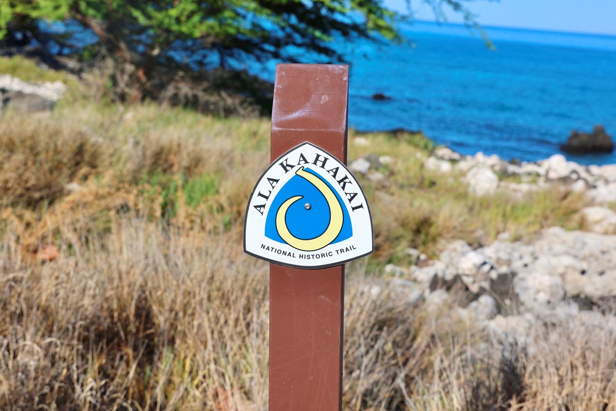 Ala Kahakai trail marker with ocean in the background