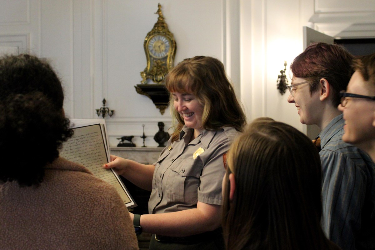 Ranger showing a historic document to visitors in a Victorian library