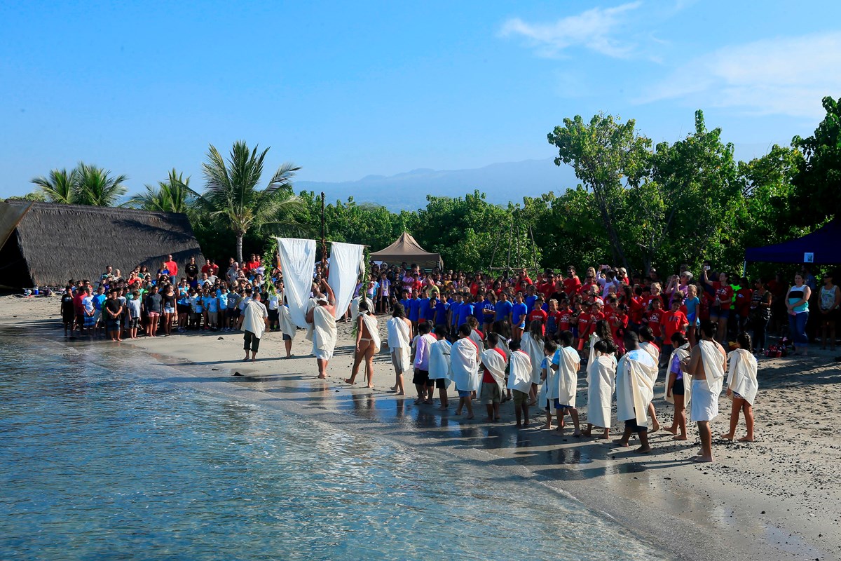 Group of kids form a traditional procession along the beach.