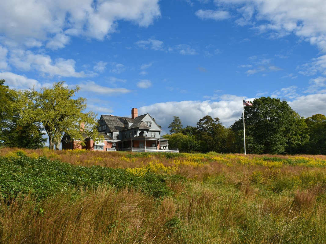A large house painted gray with green lawn and trees.