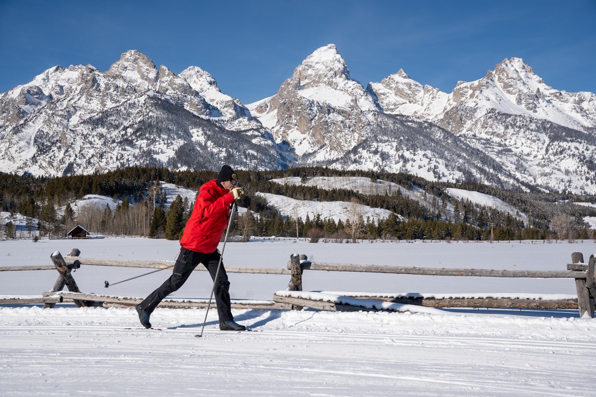 A cross country skier with snow mountains in the background