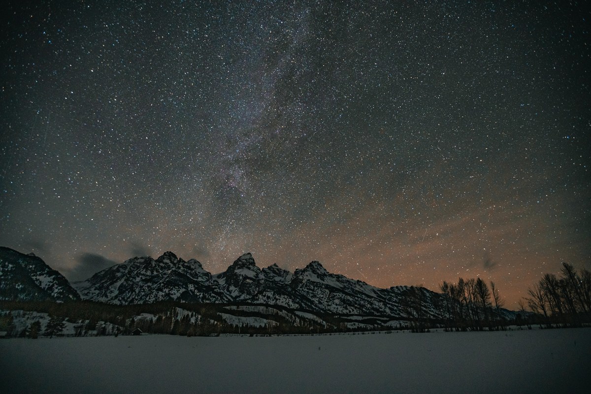 A starry night sky with snowy mountains in the foreground