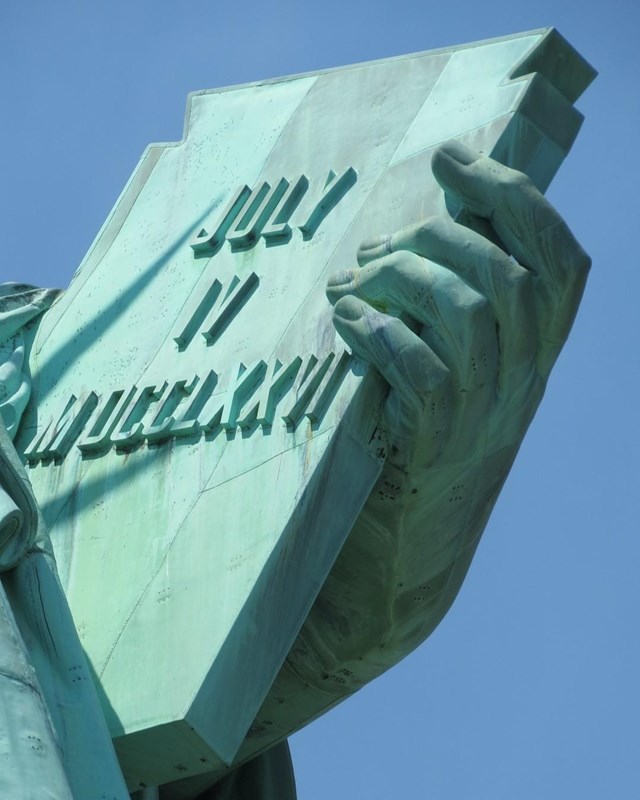 A closeup photo of the left hand and tablet of the Statue of Liberty. 