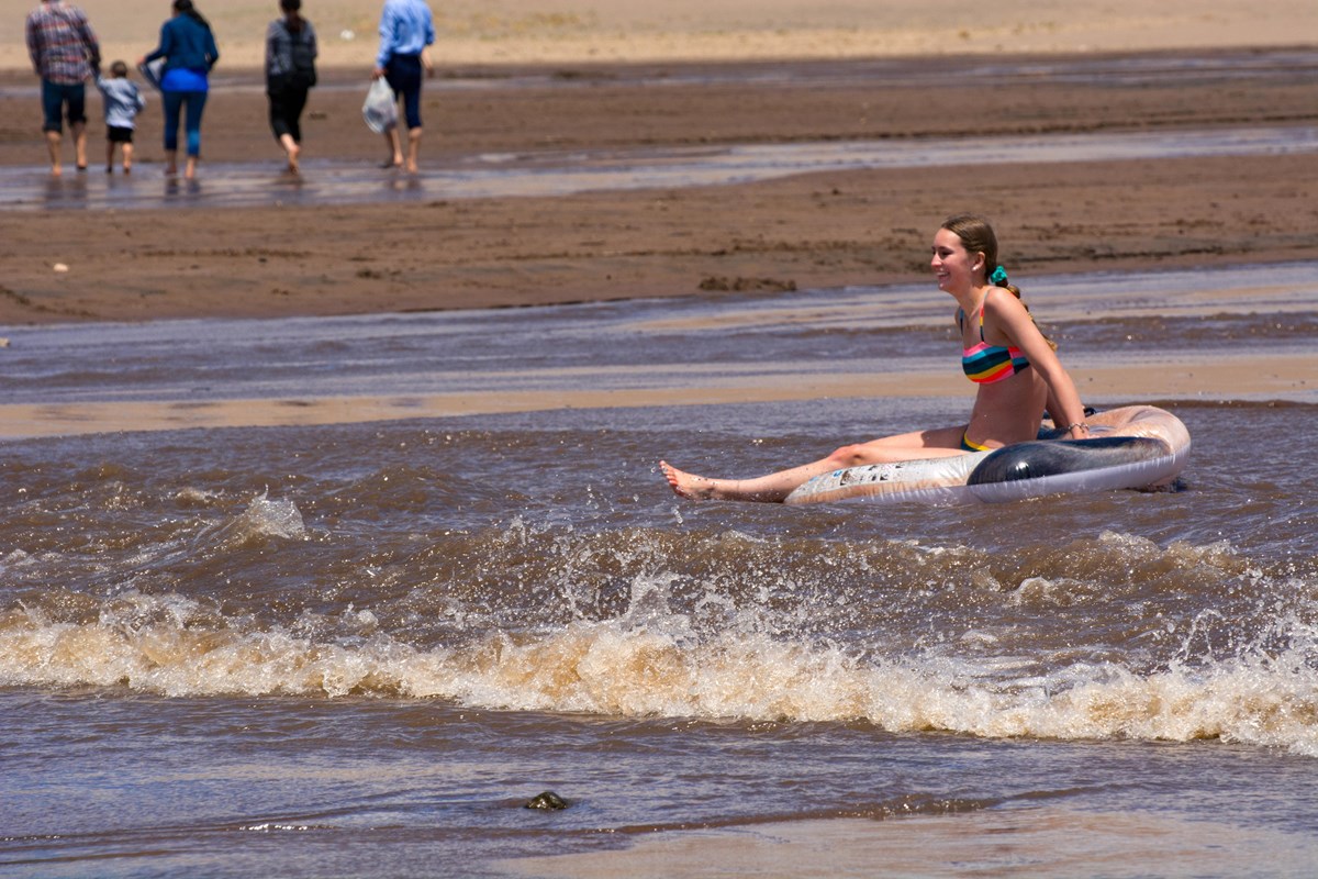 A teen girl sits on a floatation device 