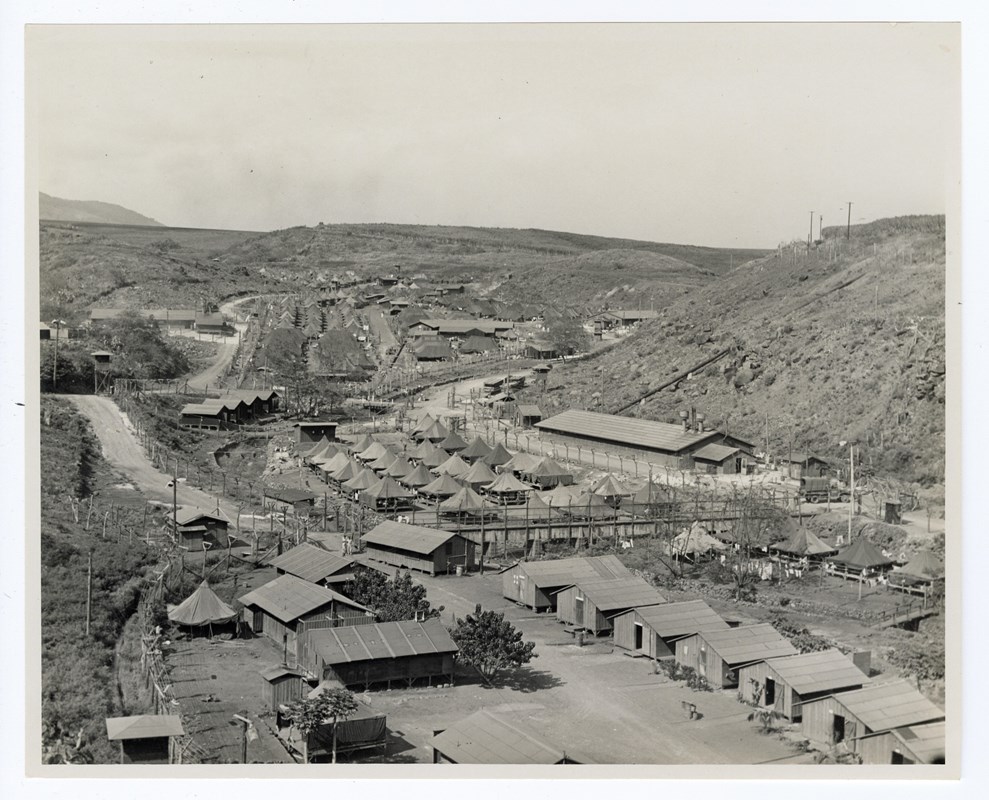 A historic photo of a valley filled with tents and wooden buildings