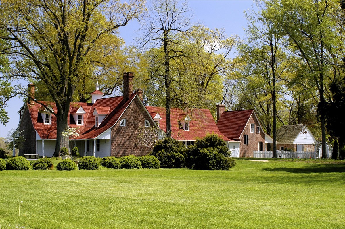 Image of a large historic house with green lawn in foreground. 